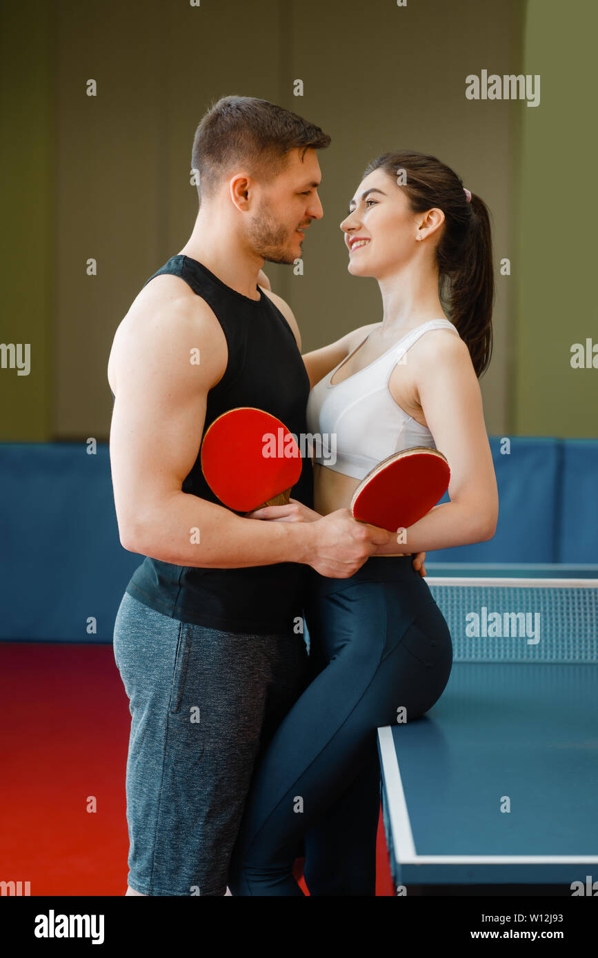 Couple avec des raquettes hugging at la table de ping-pong Banque D'Images