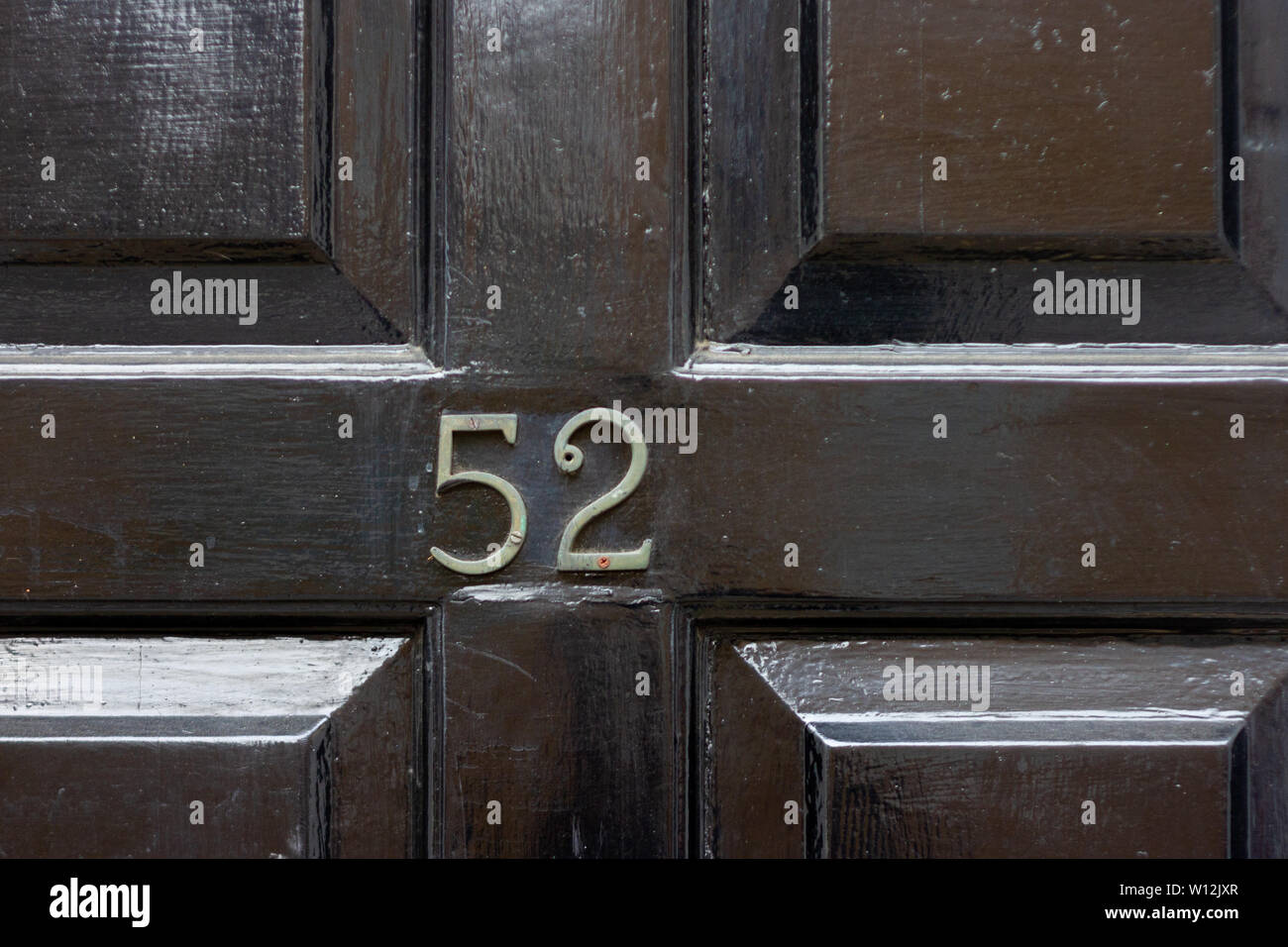 Chambre numéro 52 avec les cinquante-deux chiffres en métal peint en noir sur une porte en bois ancien Banque D'Images