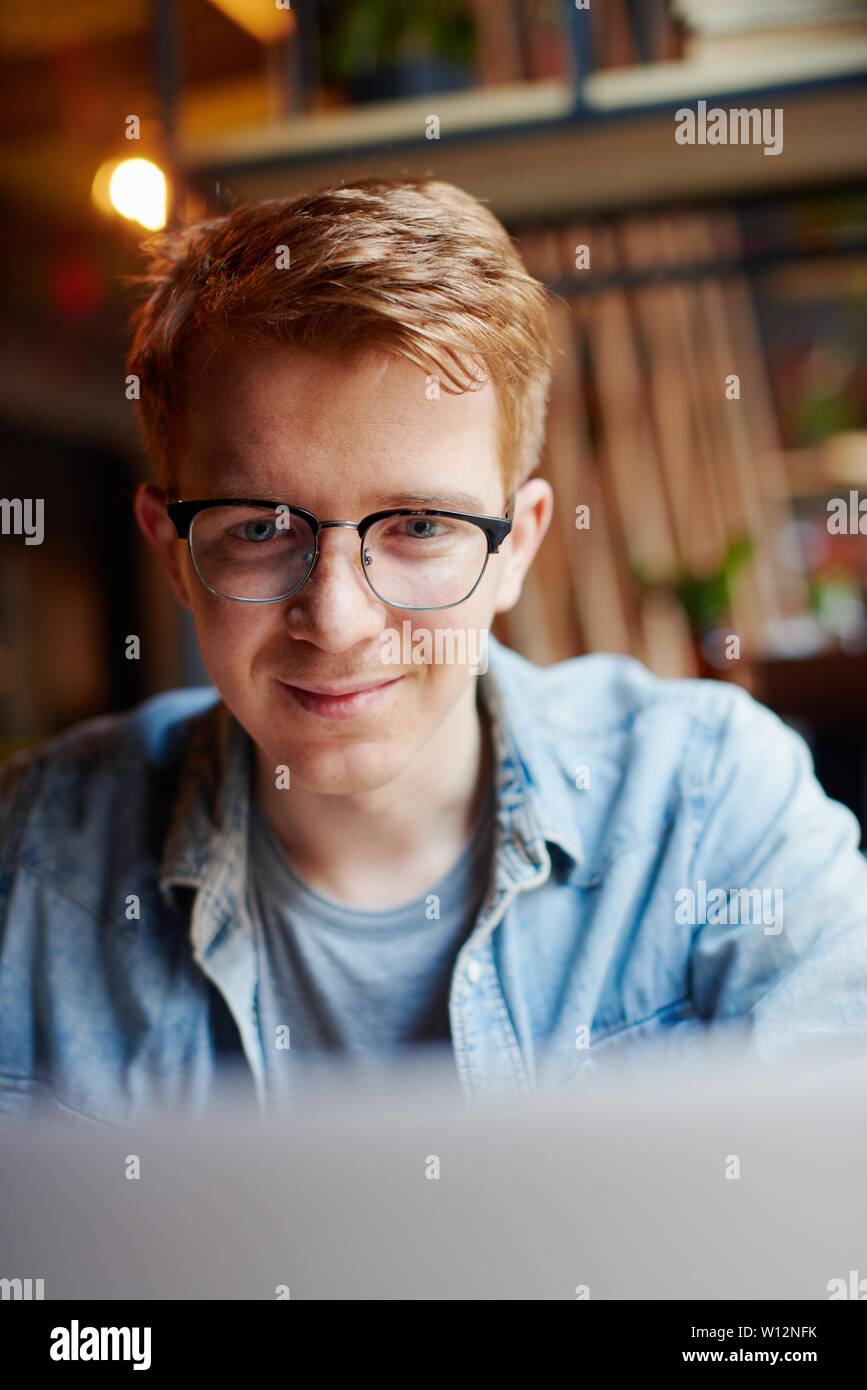 Jeune homme portant des lunettes et de regarder l'écran d'un ordinateur portable. Banque D'Images