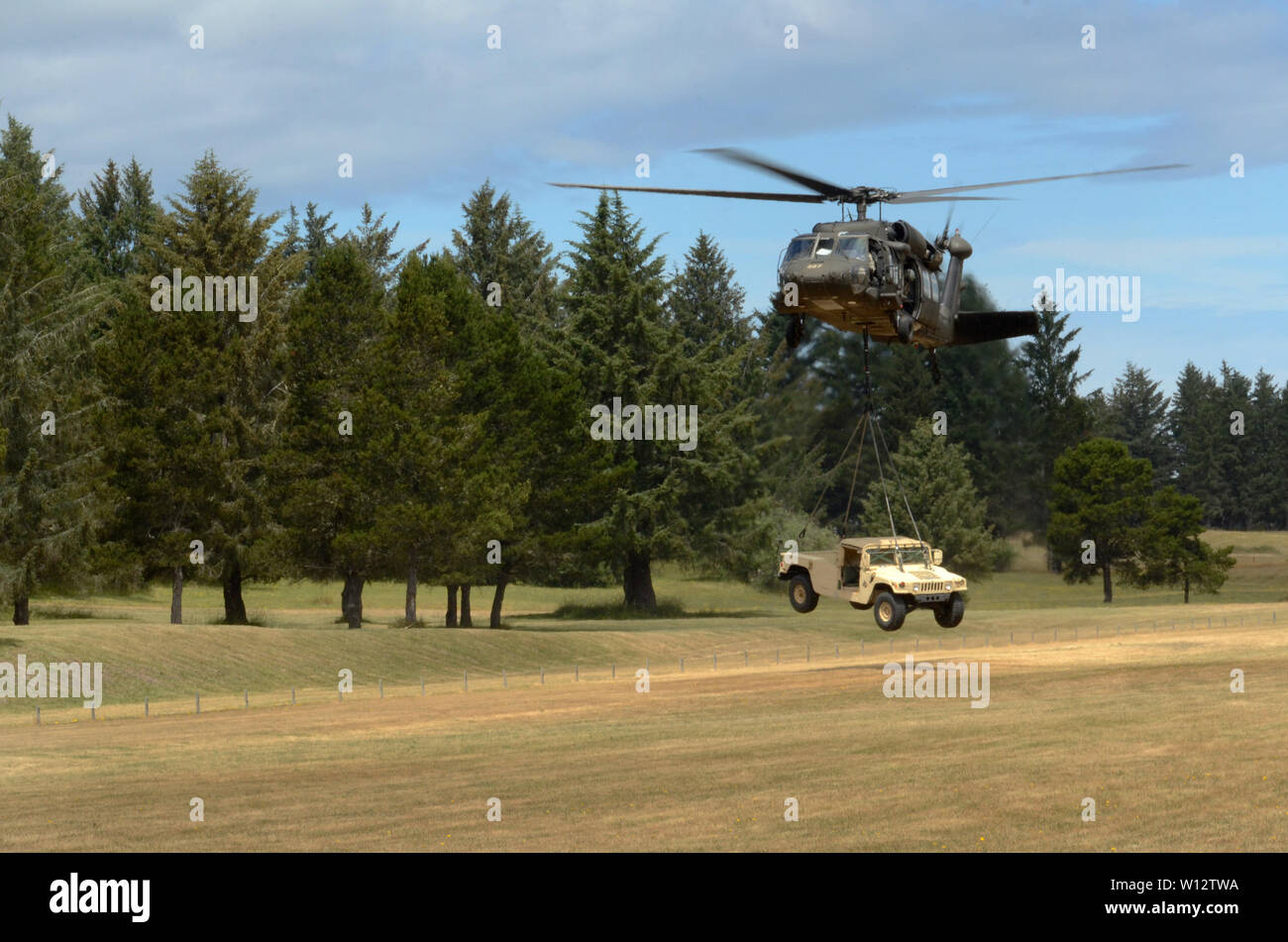 Un UH-60 Black Hawk se prépare à lever une armée forte mobilité Multipurpose roues pendant la formation d'assaut aérien au Camp Rilea, Warrenton, Oregon, le 27 juin 2019. La Garde Nationale (photo de John Hughel, Affaires publiques du Département militaire de l'Oregon) Banque D'Images