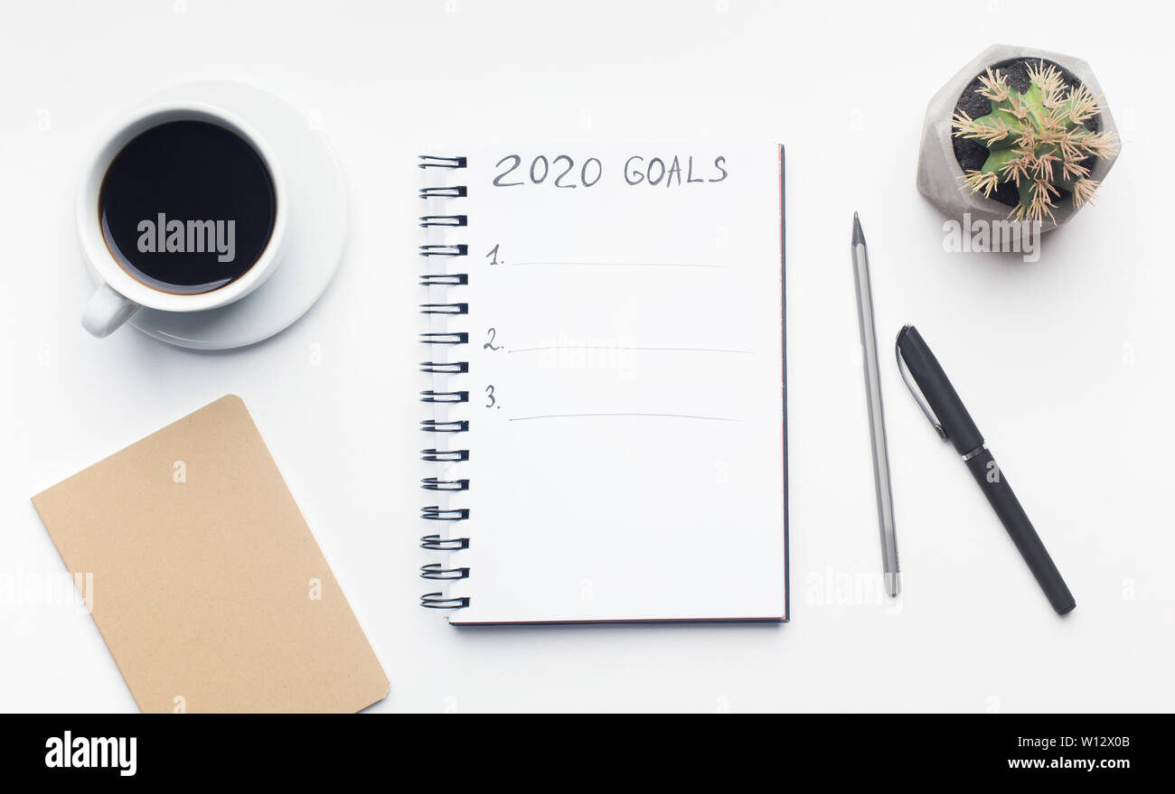 Liste des objectifs dans le bloc-notes avec stylo et tasse de café on white Banque D'Images