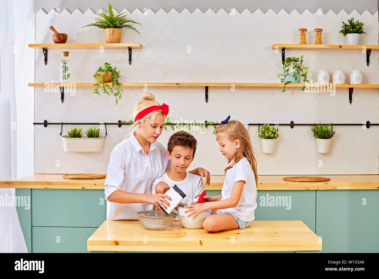 Famille heureuse dans la cuisine. la mère et l'enfant la préparation de la pâte, faire cuire des biscuits Banque D'Images