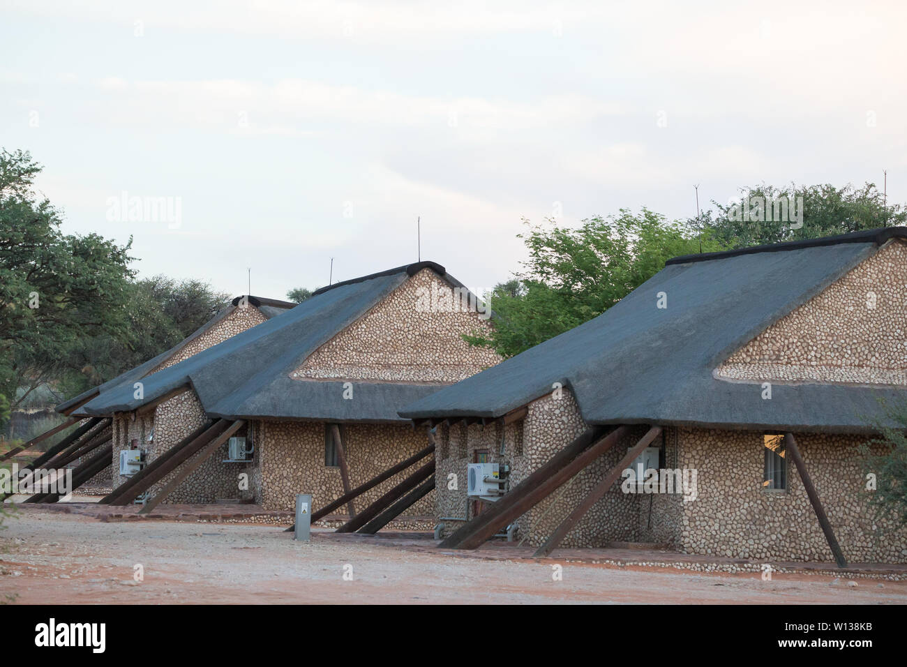 Chalets traditionnels en pierre et des huttes d'hébergement à l'architecture de style africain à Tweerivieren rest camp dans le parc transfrontalier de Kgalagadi, Afrique du Sud Banque D'Images