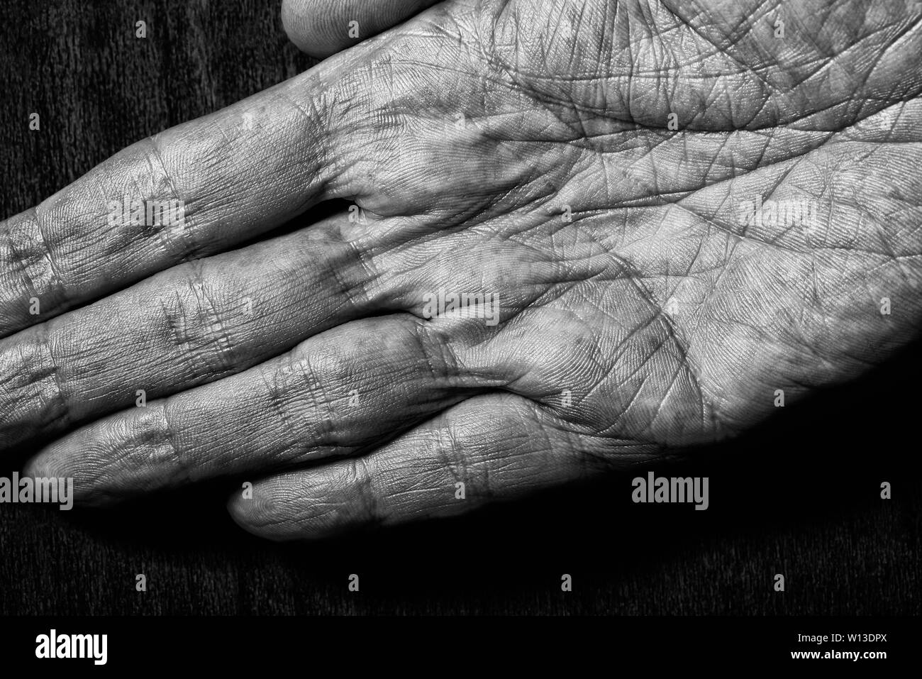 Image noir et blanc d'hommes âgés ayant les mains sur un fond sombre. Détail de la paume de la main. Banque D'Images