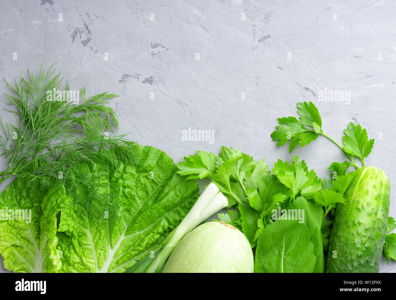 Arrière-plan avec les légumes verts, la salade, le concombre, l'oignon vert et les courgettes sur la table en pierre grise. Concept d'aliments sains avec copie espace. Banque D'Images