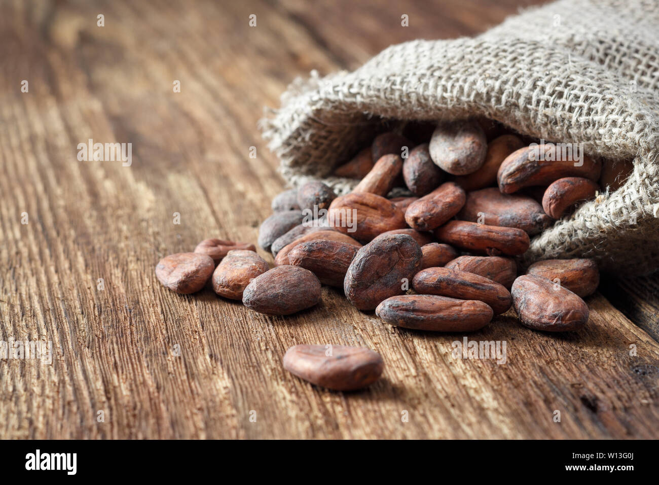 Fèves de cacao dans un sac sac sur un fond de bois Photo Stock - Alamy