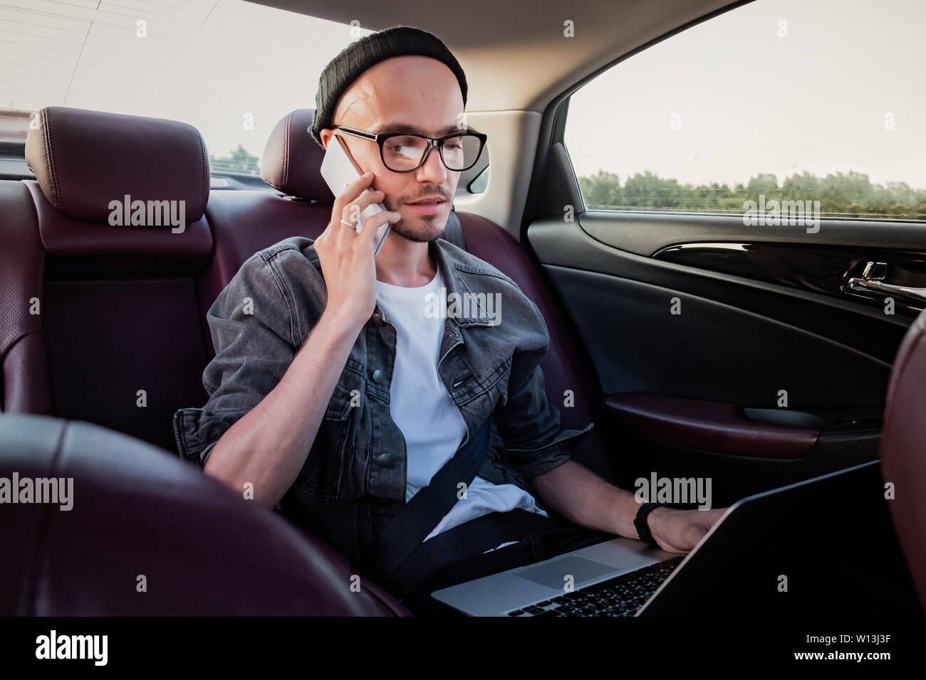 Man making phone call sur une banquette arrière d'une voiture sur Voyage au travail. Personne de sexe masculin à l'aide de la technologie moderne lors des trajets d'un secteur ou de location c Banque D'Images