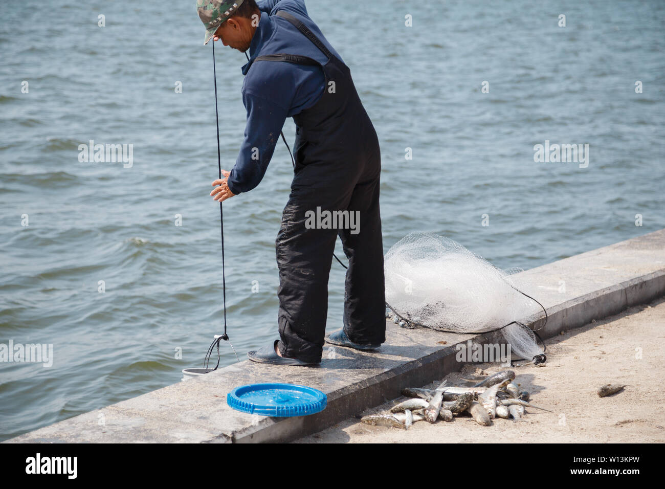 Un homme de mettre de l'eau dans le seau pour le poisson qu'il vient de prendre avec filet de pêche en rivière banane off Cocoa Beach, Floride, USA. Banque D'Images