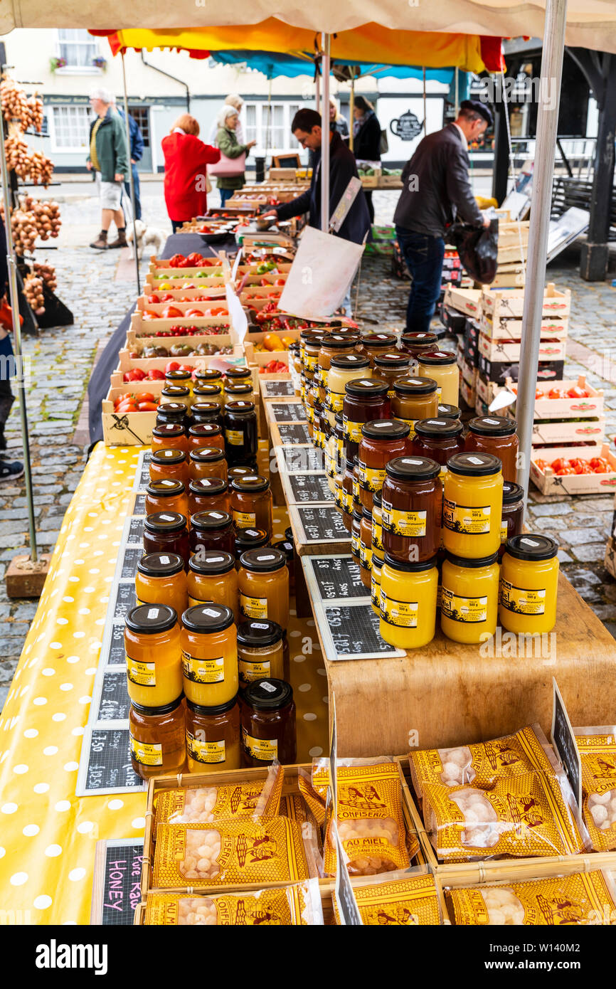 Vue le long marché français stall empilées dans le premier plan avec bols de divers types de miel avec des boîtes de tomates en arrière-plan. Banque D'Images