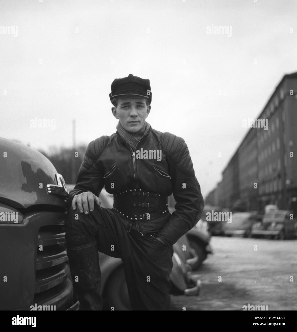 Motocycliste dans les années 1950. Un jeune homme vêtu de la façon typique les motards ont fait dans les années 1950. Tout en cuir. Bottes en cuir, pantalon et veste. A une ceinture et un chapeau typique motocycliste. La Suède Décembre 1954 Banque D'Images