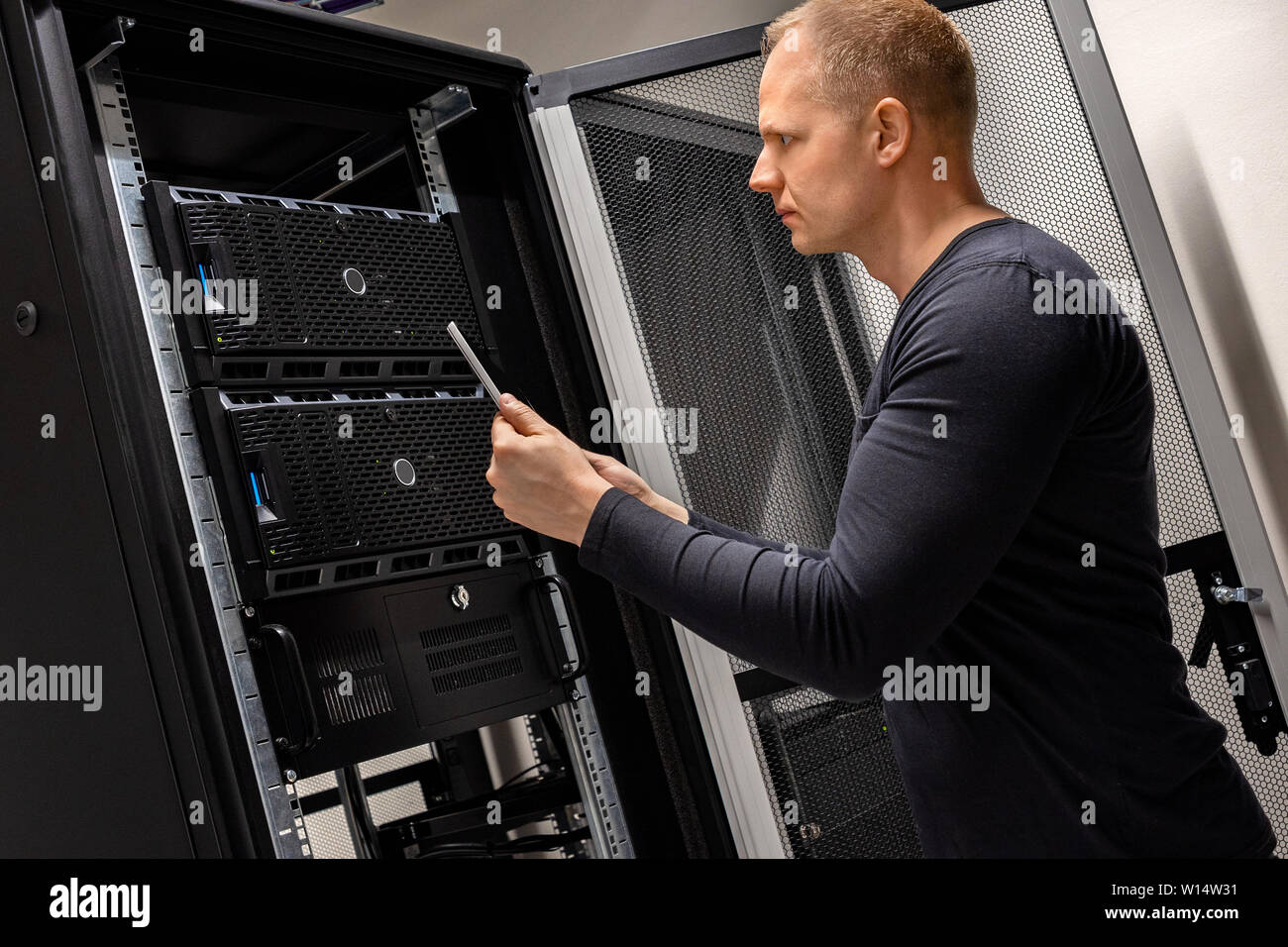 Il Soutenir Holding Digital Tablet l'analyse des serveurs et réseau en datacenter Banque D'Images