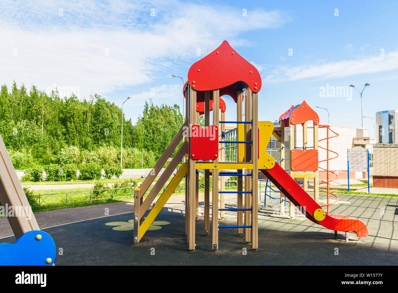 Jeux pour enfants sur les activités de la cour en parc public entouré d'arbres verts à la lumière du soleil le matin. Les enfants courir, toboggan, balançoire, balançoire sur playg moderne Banque D'Images