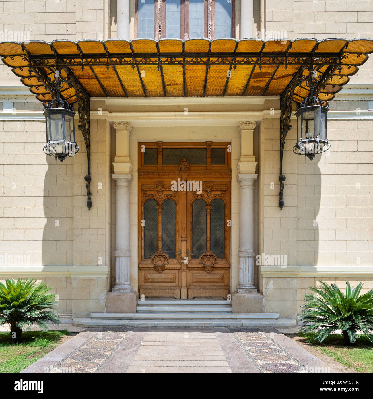 Décorées de meubles anciens en bois porte dans un mur de briques en pierre, parasol et deux lanternes, façade de Palais Abdine, Le Caire, Egypte Banque D'Images