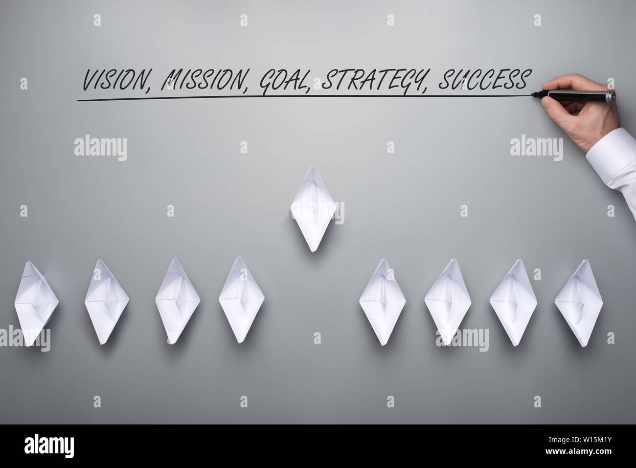 Flotte de bateaux origami papier faite avec une vision, mission, objectif, stratégie et le succès signe au-dessus de eux. Sur fond gris. Banque D'Images