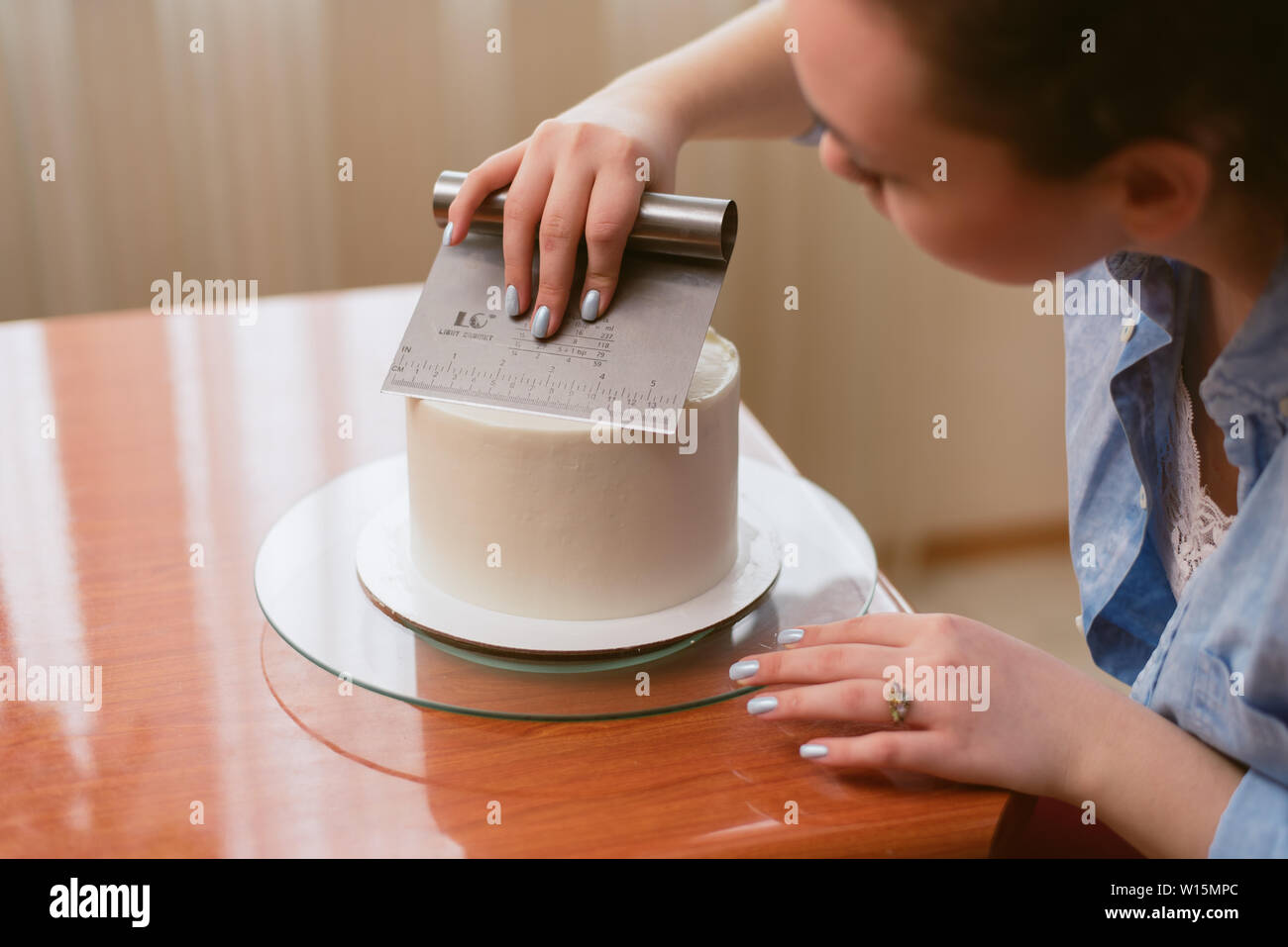 Une Jolie Fille Faire Un Gateau Dans Une Boulangerie La Jeune Fille Lisse La Creme Sur Le Gateau Gateau Blanc Sur Une Table En Bois Photo Stock Alamy