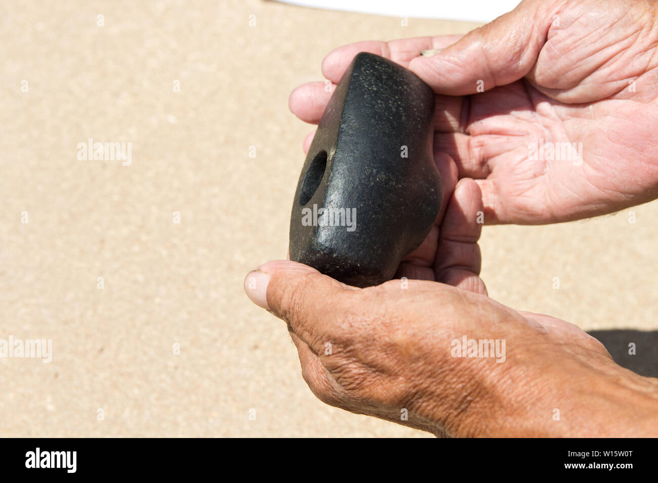 Un vieux marteau de pierre un homme âgé tient dans ses mains. L'archéologie. Étude des objets anciens Banque D'Images