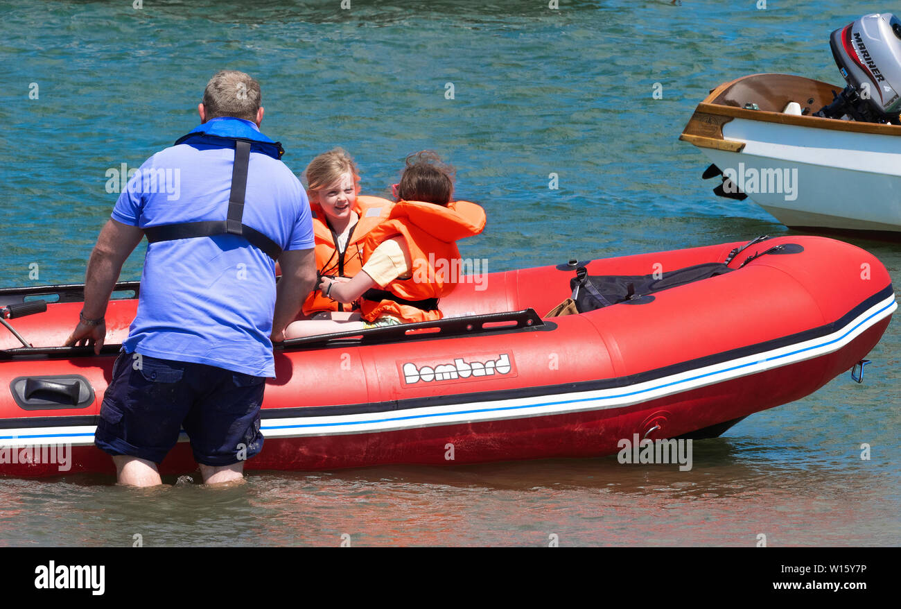 Père entrer dans gonflables en caoutchouc avec deux jeunes enfants dans les gilets au large de la tête, le port de Chichester, West Sussex, England, UK Banque D'Images