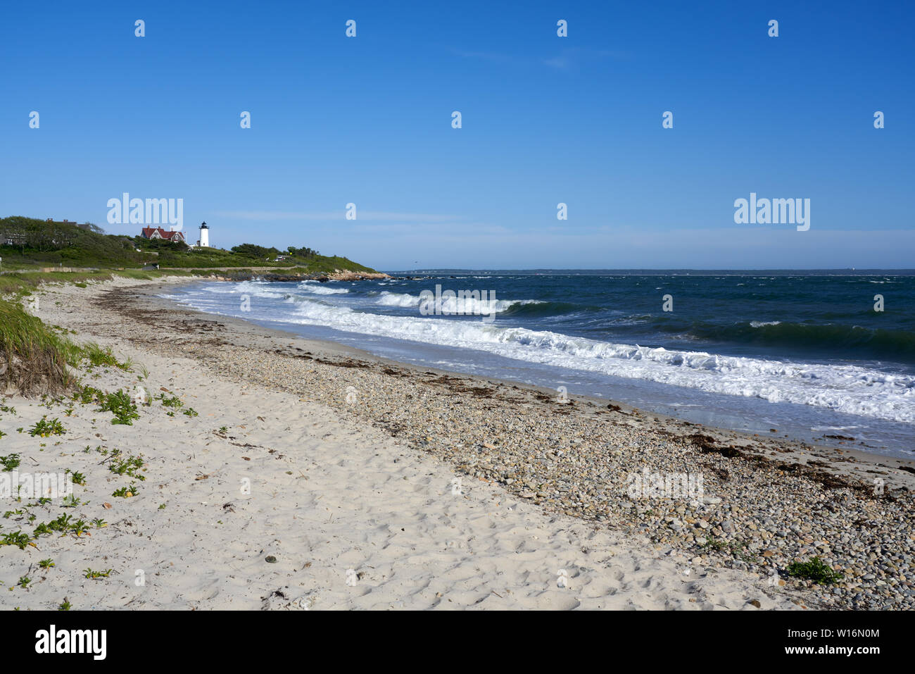 Plage de sable fin et des vagues avec lumière Nobska lighthouse dans la distance Banque D'Images
