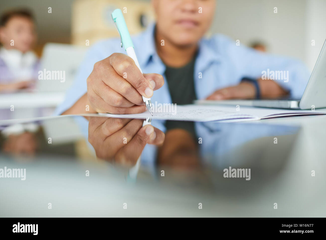 Close-up of busy black woman sitting at table et prendre des notes du classeur tout en travaillant avec l'information en bibliothèque Banque D'Images