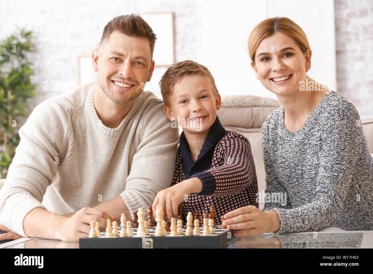 Couple heureux avec peu d'enfants adoptés en jouant aux échecs à la maison Banque D'Images