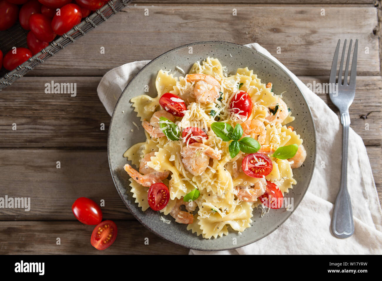 Farfalle pâtes italiennes dans une sauce crémeuse aux crevettes sauce à l'ail, tomates cerises et basilic sur une assiette, vue d'en haut. Copy space Banque D'Images