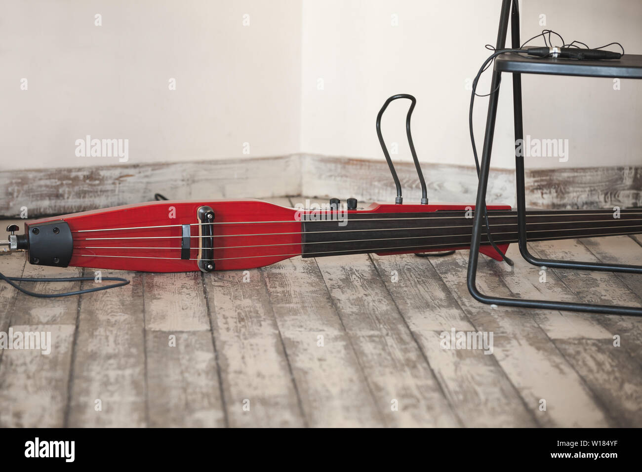Musique live, fond rouge contrebasse électrique moderne repose sur un plancher en bois de grungy studio de musique, photo en gros plan avec selective focus Banque D'Images