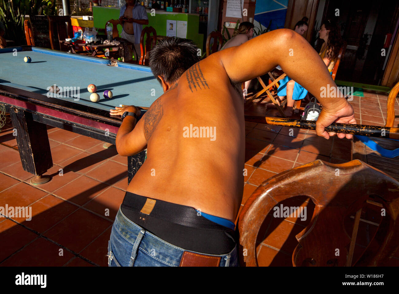 Un homme avec des tatouages sur son dos est en jouant au billard dans une auberge à Siem Reap, Cambodge. Banque D'Images