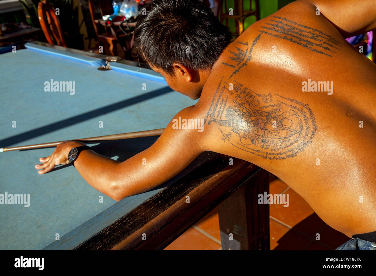 Un homme avec des tatouages sur son dos est en jouant au billard dans une auberge à Siem Reap, Cambodge. Banque D'Images