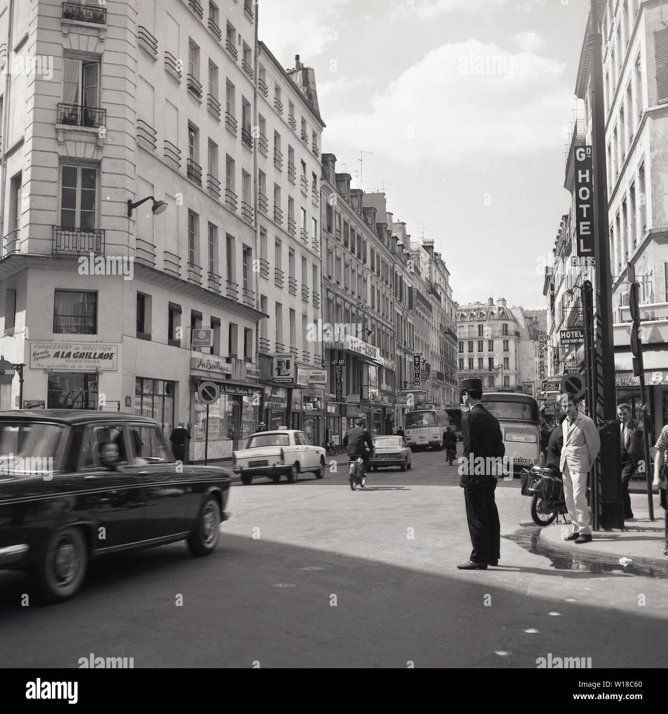 Années 1960, historique, Paris, France, scène de rue avec un policier français de la circulation, membre de la police nationale, debout au coin d'une route. Banque D'Images
