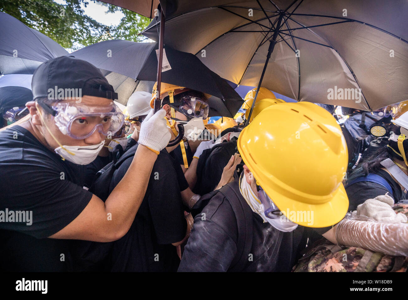 Des manifestants anti gouvernement utiliser parasols comme boucliers, ils ont également porter des engins tels demandez des masques à gaz, casques et lunettes de sécurité pour eux-mêmes la défense de jet de poivre de la police et des gaz lacrymogènes alors qu'ils tentent de prendre d'assaut le bâtiment du Conseil législatif.Des centaines de manifestants se rassemblent à l'extérieur du bâtiment du Conseil législatif et tentent de forcer le passage et occuper le parlement de Hong Kong le 1 juillet que le territoire a marqué l'anniversaire de sa 22e anniversaire rétrocession à la Chine. Banque D'Images