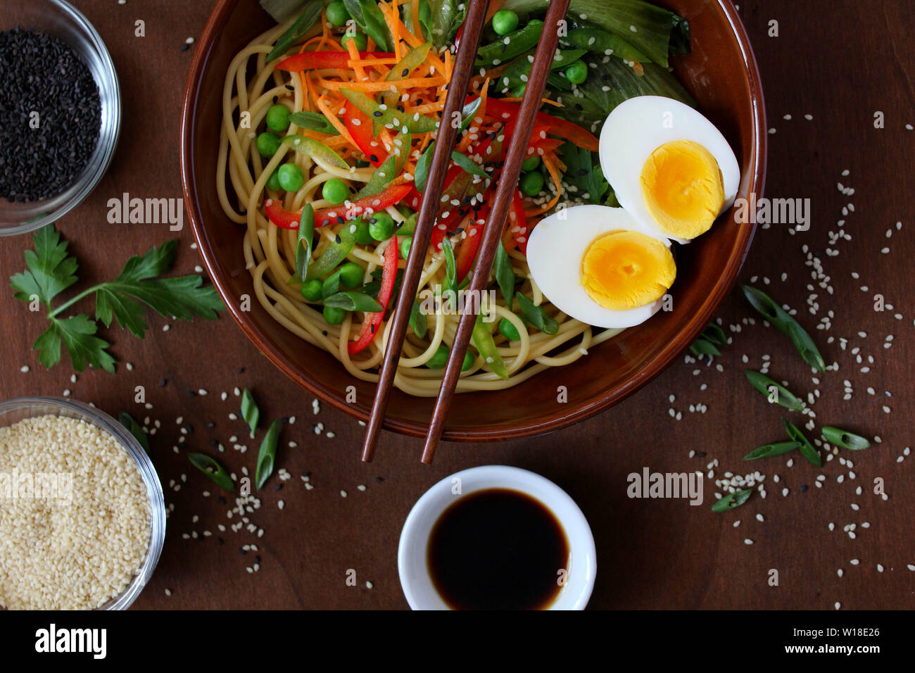 Les nouilles avec les légumes et les œufs dans un bol sur fond sombre. Vue de dessus avec l'exemplaire de l'espace. La cuisine asiatique. Banque D'Images