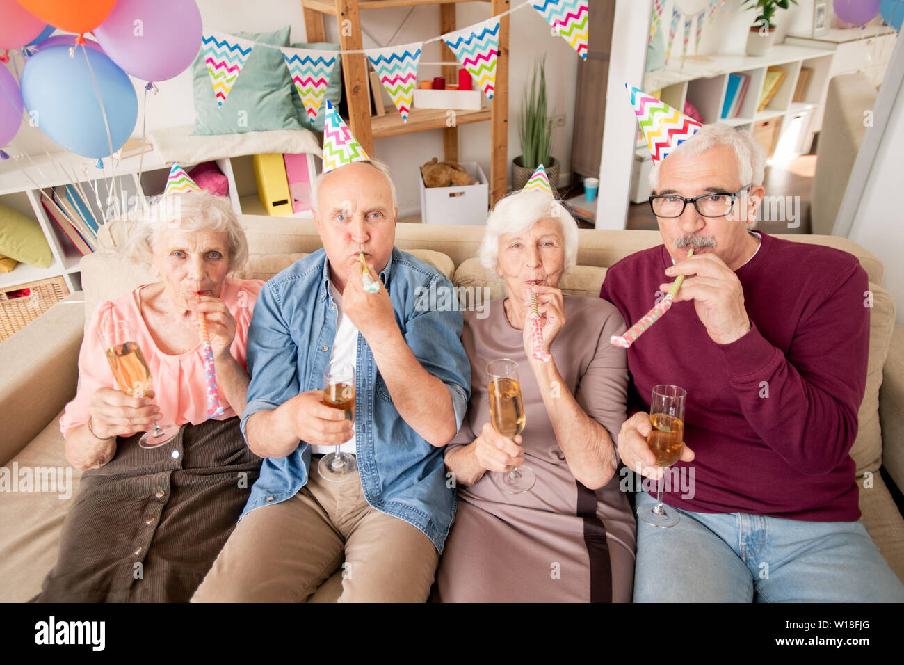 Groupe d'amis ou pour deux couples avec des sifflets de soufflage champagne at Birthday party Banque D'Images