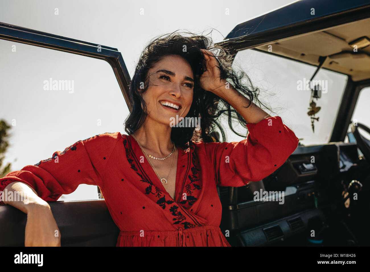 Belle Jeune femme debout près de la voiture avec cheveux volant dans l'air. Les femmes de race blanche sur les vacances d'été. Banque D'Images