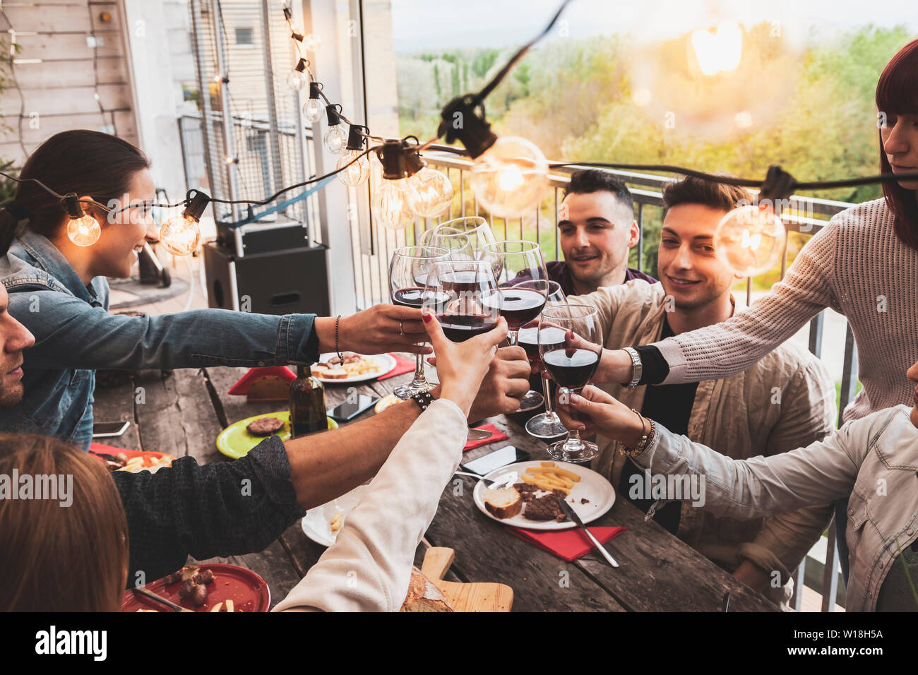 Groupe d'amis heureux de boire du vin rouge et manger une pizza à la ...