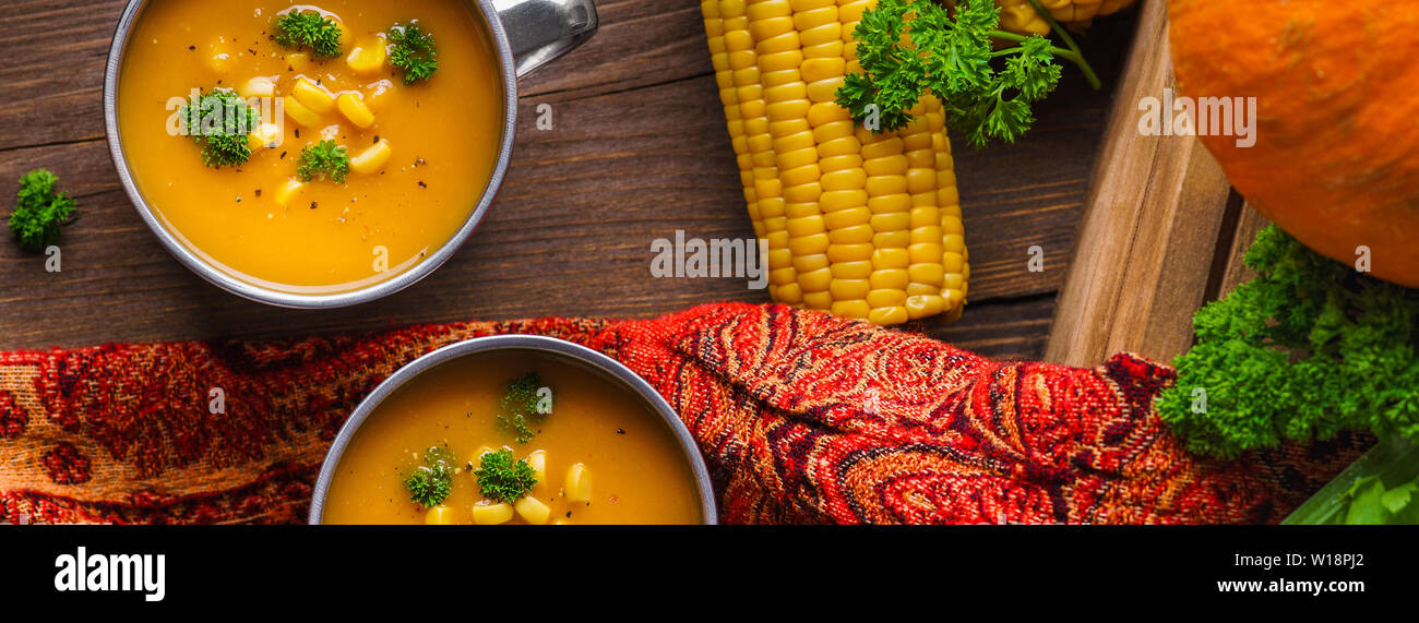 Soupe de potiron dans un mug servi avec le maïs et le persil. Le déjeuner d'automne sain concept avec légumes frais overhead shot. Banque D'Images