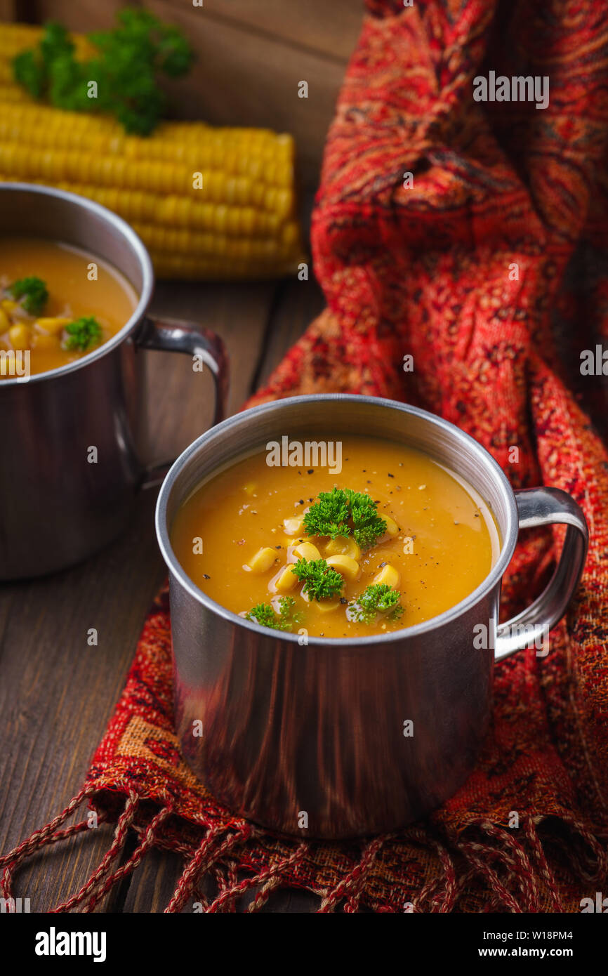 Une tasse de soupe au potiron servi avec le maïs et le persil sur une table en bois. Le déjeuner d'automne sain concept Banque D'Images