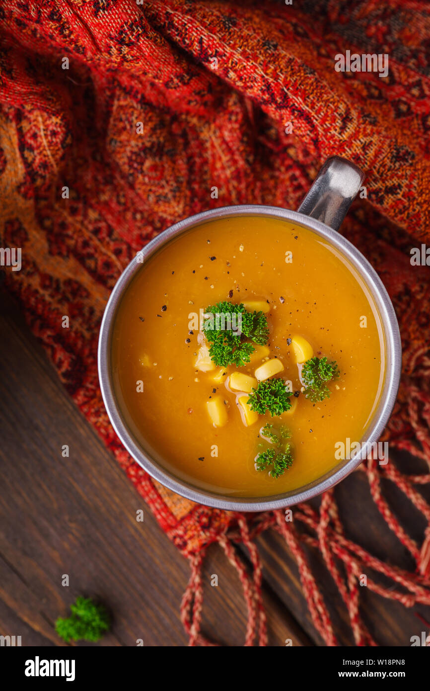Une tasse de soupe au potiron servi avec le maïs et le persil frais généraux shot. Automne sain le déjeuner. Banque D'Images