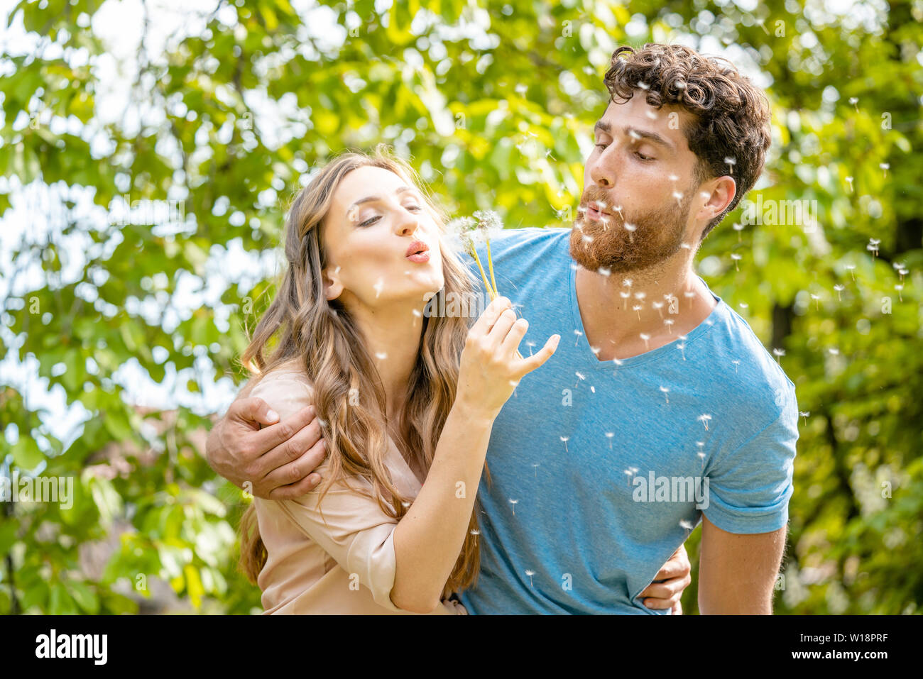 Jeune couple à rêver de leur avenir blowing dandelion seeds Banque D'Images
