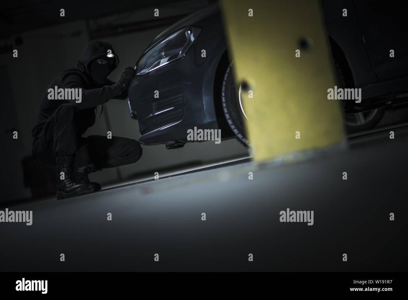 Voleur de voiture essayant d'ouvrir le capot du véhicule pour obtenir  l'accès aux système d'alarme. Parking public à la nuit. Grand Theft Auto  Thème Photo Stock - Alamy