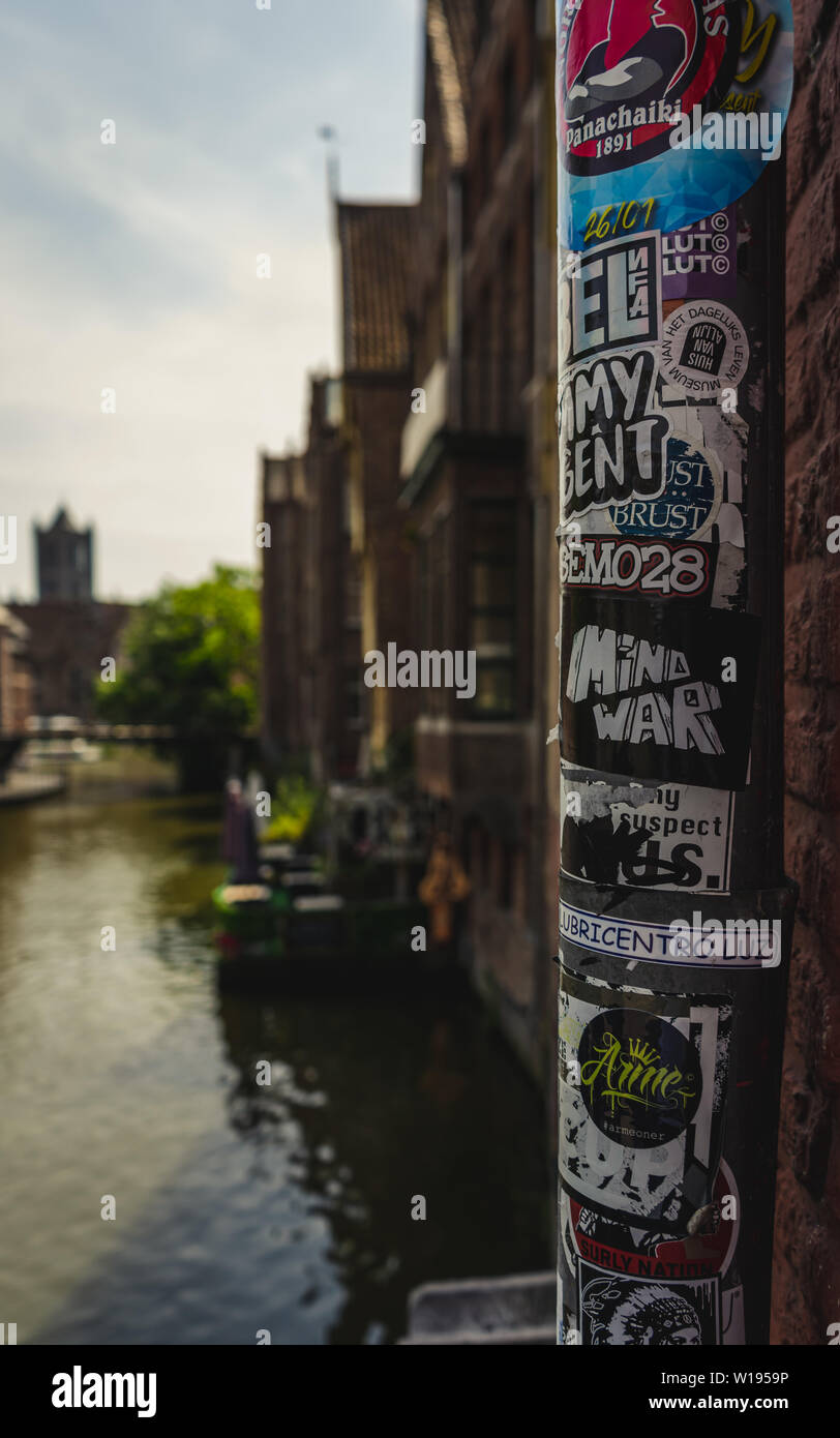 Close up of urban autocollants sur pilier, par l'eau et de l'beffroi de Gand dans l'arrière-plan Banque D'Images