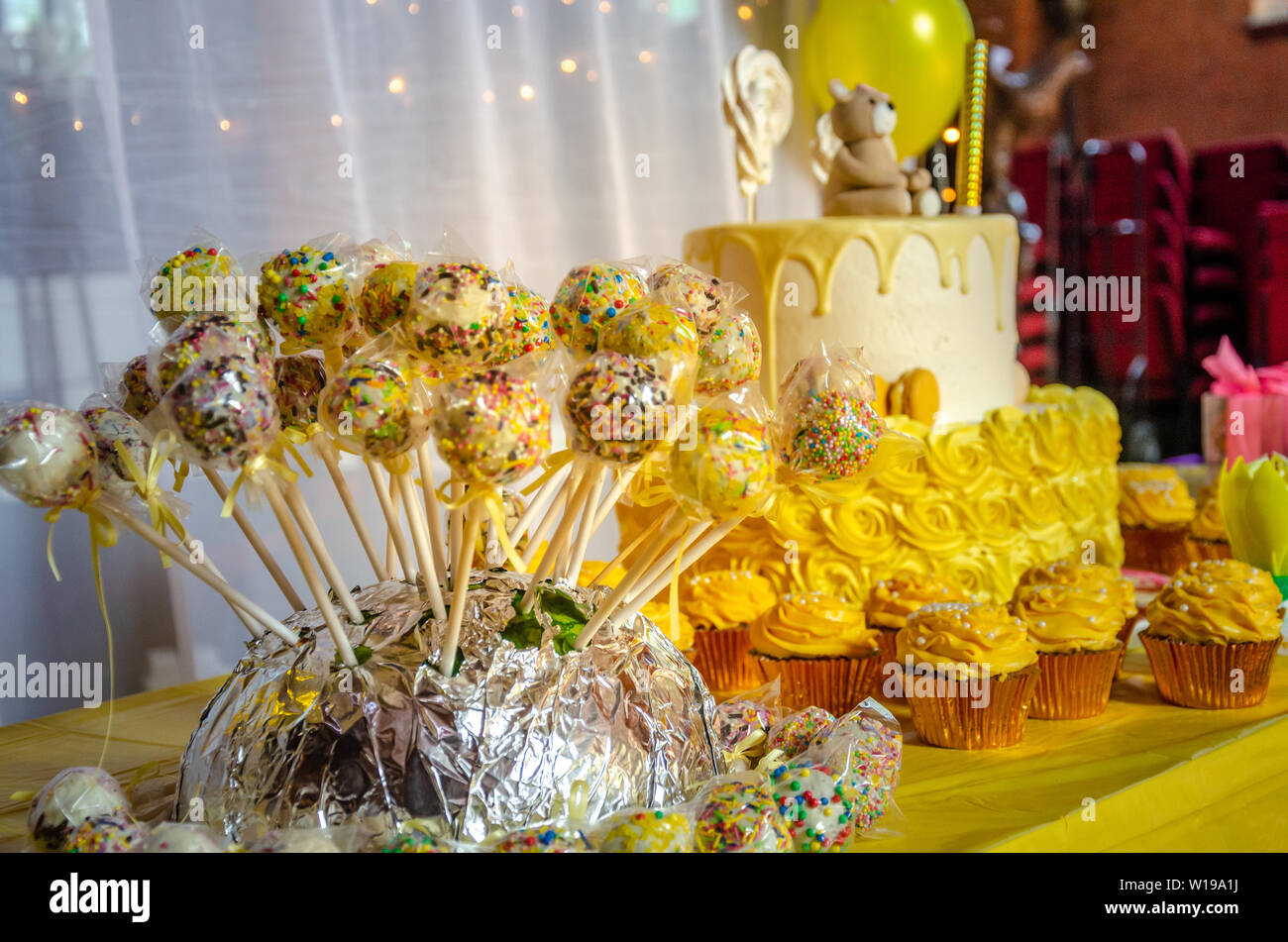 Une table avec un gâteau, des petits gâteaux et un jaune cake pops et une célébration d'anniversaire. Banque D'Images