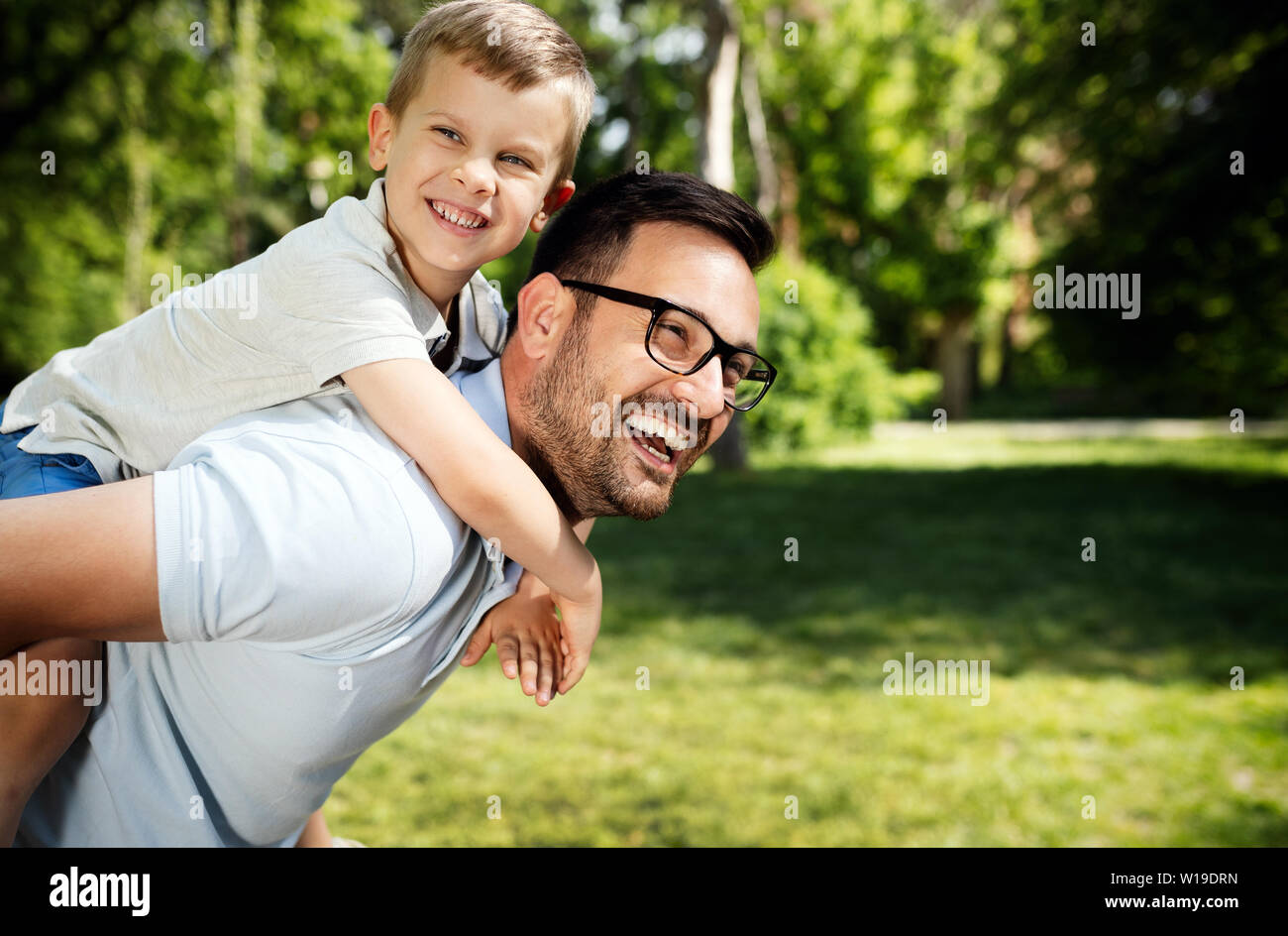 Père portant son fils sur le dos et smiling outdoors Banque D'Images
