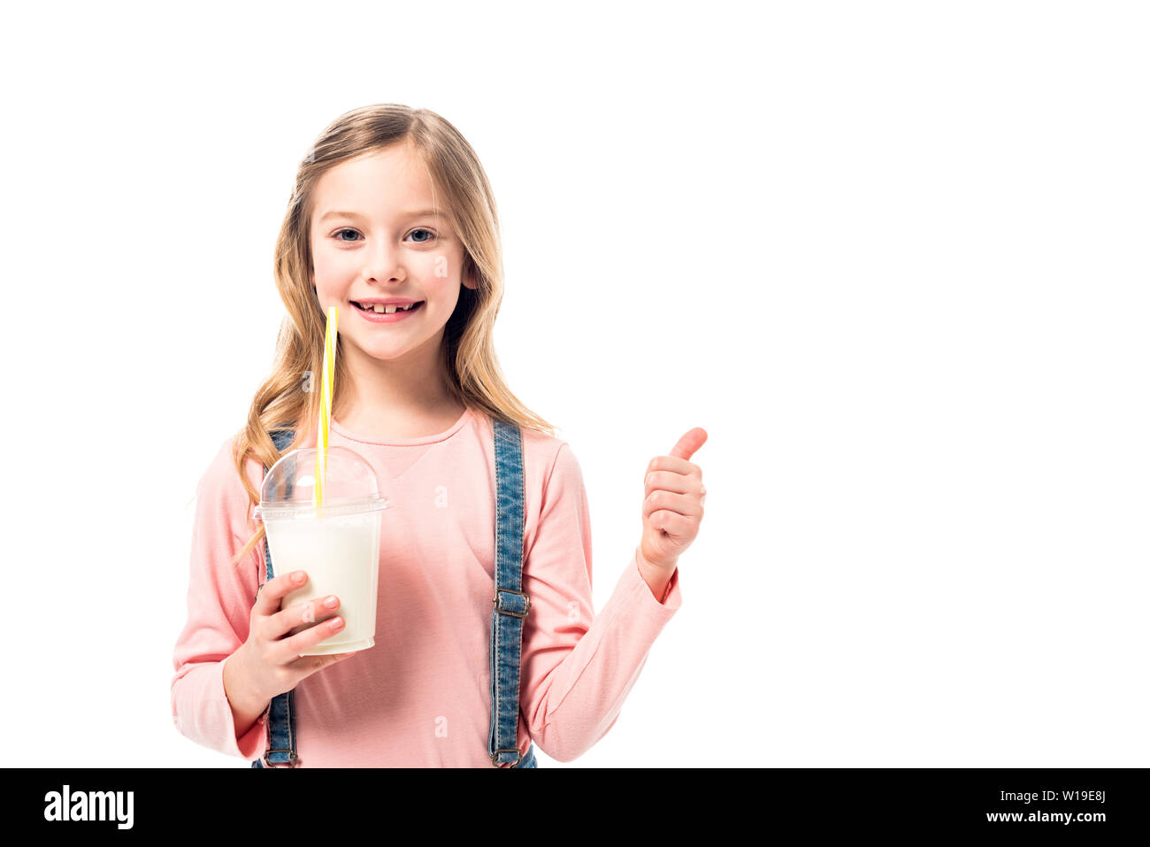 Smiling kid holding milkshake et showing thumb up isolated on white Banque D'Images