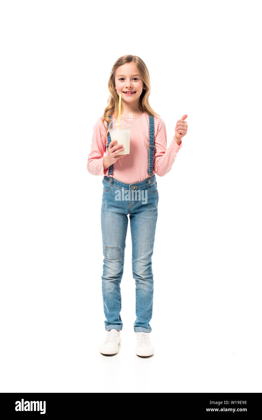 Vue pleine longueur de smiling kid holding milkshake et showing thumb up isolated on white Banque D'Images