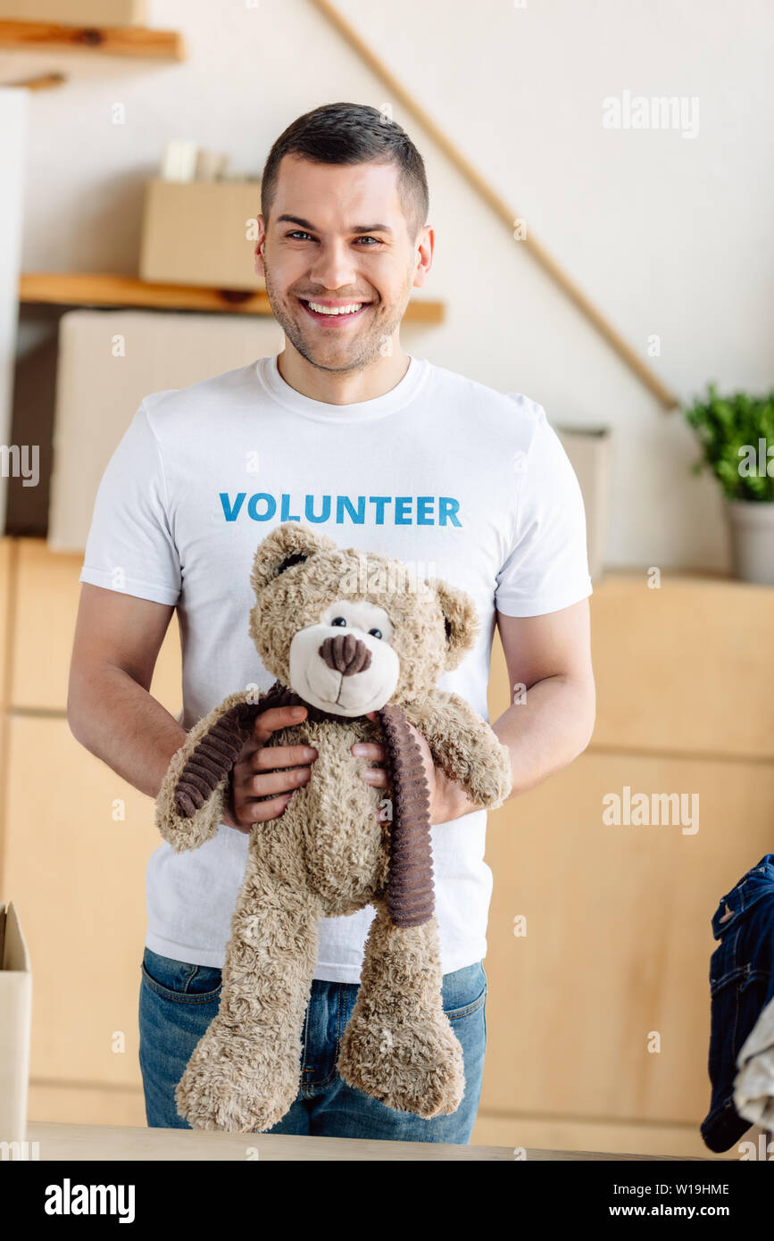 Beau, bénévoles souriants et teddy bear looking at camera Banque D'Images