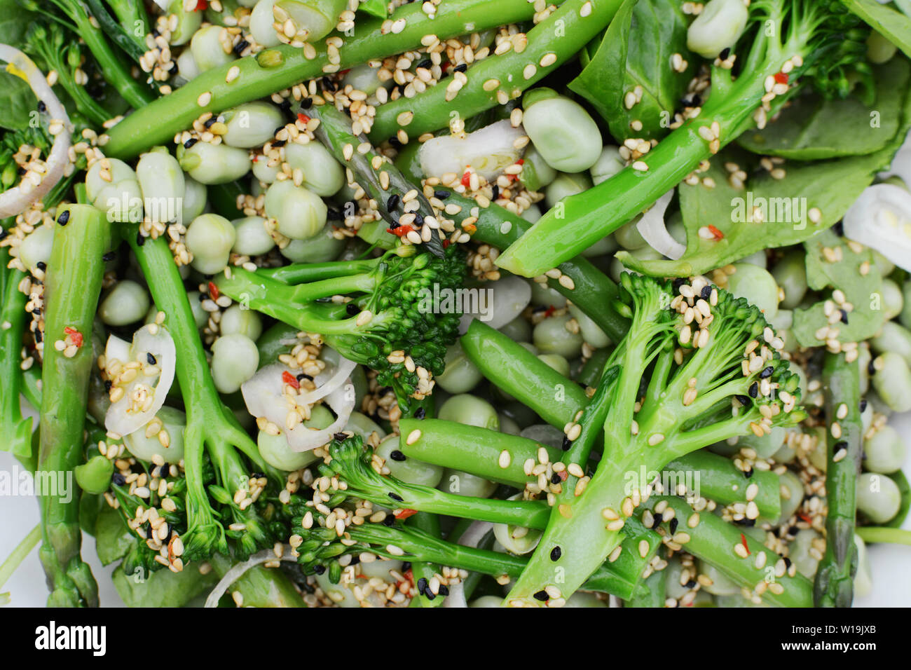 Vert printemps salade composée de tiges broccolini, fèves et haricots verts, parsemé de graines de sésame, graines de nigelle et de l'échalote Banque D'Images