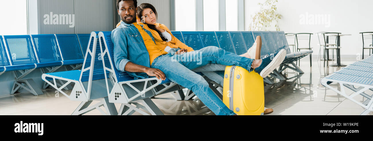 Fatigué de african american couple assis en salle d'embarquement avec valise et l'attente pour le vol Banque D'Images