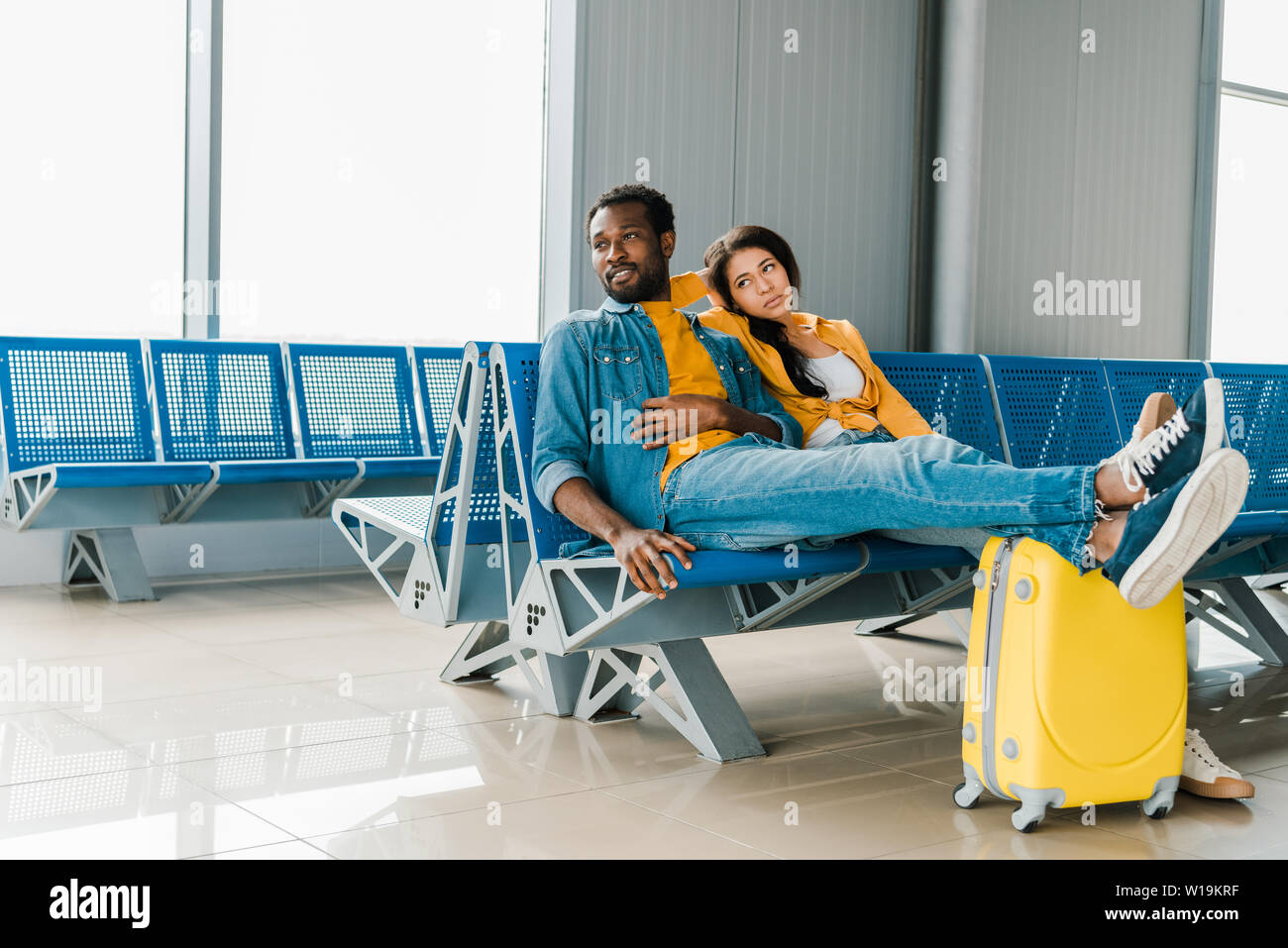 Fatigué african american couple assis en salle d'embarquement avec valise et l'attente pour le vol Banque D'Images