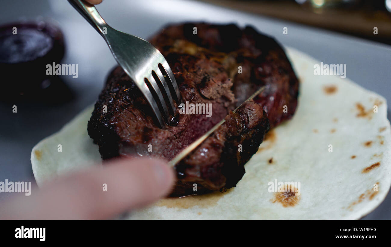 Mens mains couper des morceaux de viande juteuse. Il Coupe bifteck sur le pain pita. Photos pour le restaurant menu Banque D'Images