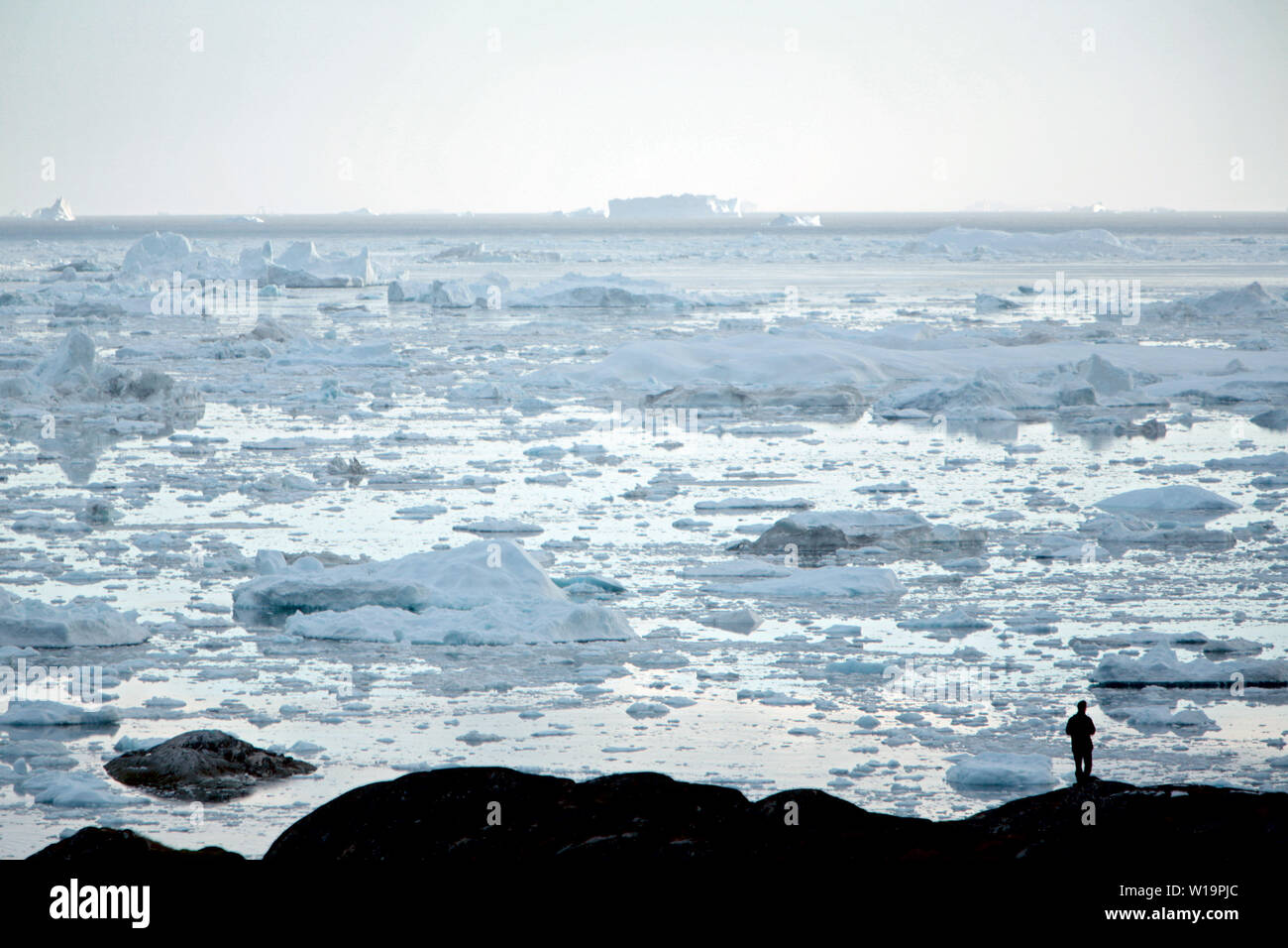 Un homme à la recherche de l'icebergs au glacier Sermeq Kujalleq, alias le glacier d'Ilulissat. Les glaciers du Groenland fondent beaucoup plus vite que prévu précédemment. Avant 2004 la glace à l'intérieur donnait entre 50 - 100 000 kilomètres cubes d'eau de fonte par an. Nouveaux chiffres indiquent que ce nombre est maintenant jusqu'à 300,000, soit une augmentation de 400 pour cent. Banque D'Images